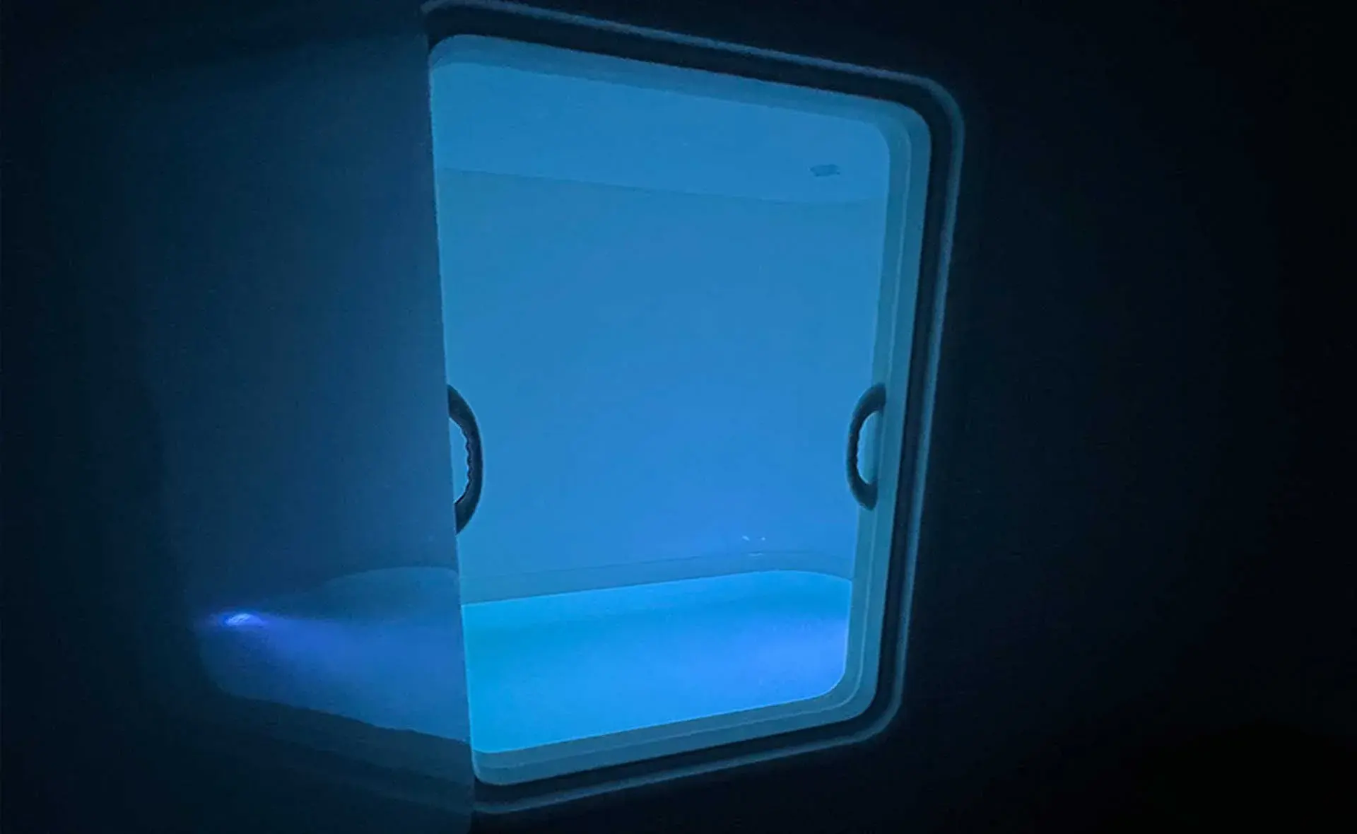 Harmony zero-gravity float tank glowing softly in a dark room